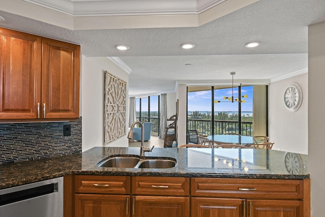 kitchen featuring dark stone countertops, dishwasher, hanging light fixtures, and crown molding