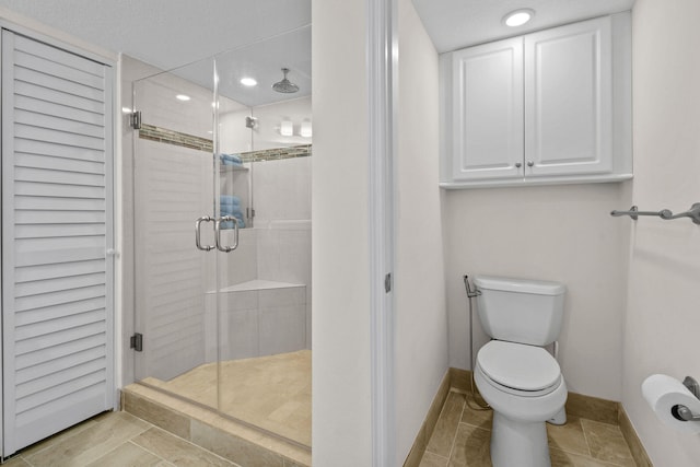 bathroom featuring a textured ceiling, tile patterned flooring, toilet, and an enclosed shower