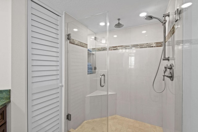 bathroom featuring a shower with door, vanity, and a textured ceiling