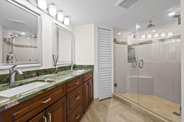 bathroom featuring an enclosed shower, vanity, and a textured ceiling