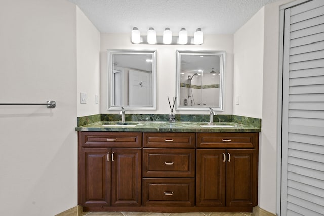 bathroom with tile patterned flooring, vanity, and a textured ceiling