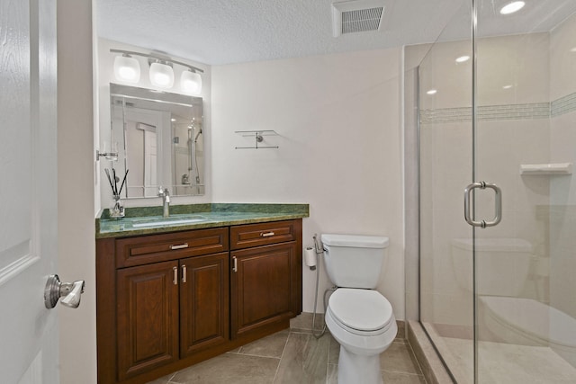 bathroom featuring vanity, tile patterned flooring, a textured ceiling, a shower with shower door, and toilet