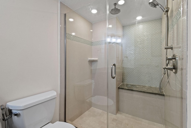 bathroom with a shower with shower door, toilet, and tile patterned flooring