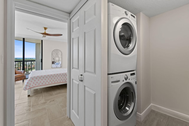 clothes washing area featuring stacked washing maching and dryer, a textured ceiling, and ceiling fan