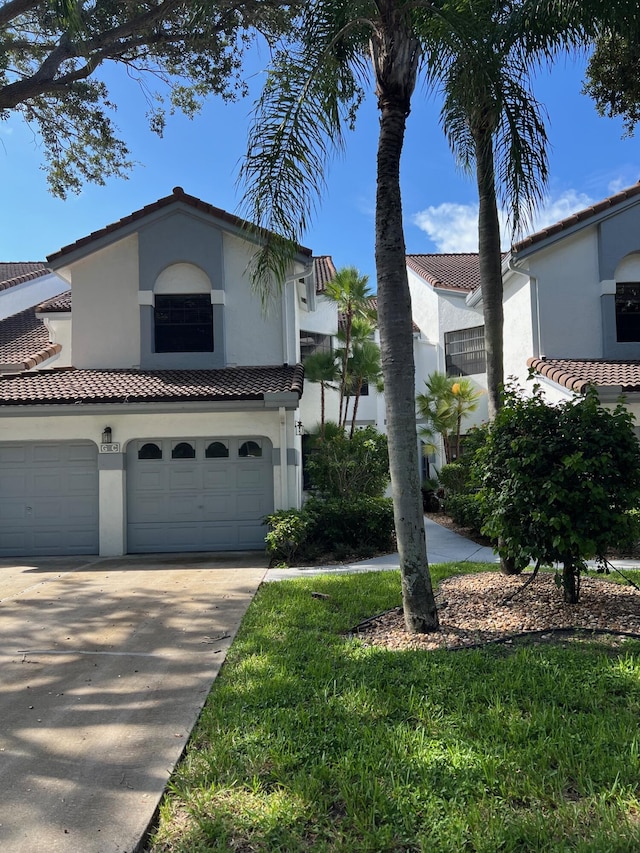 mediterranean / spanish-style house with stucco siding, a tile roof, and concrete driveway