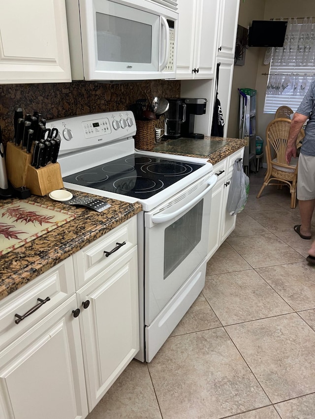 kitchen featuring white cabinets, dark stone countertops, white appliances, and light tile patterned floors