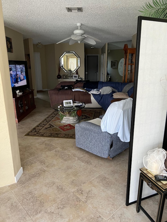 living room featuring tile patterned flooring, a textured ceiling, and ceiling fan