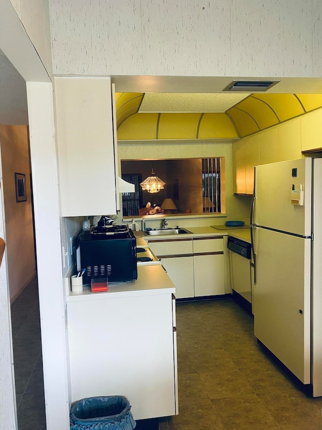 kitchen with kitchen peninsula, dishwashing machine, sink, white cabinets, and white fridge