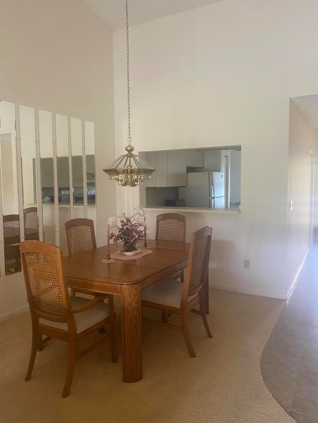 carpeted dining space featuring a chandelier and high vaulted ceiling