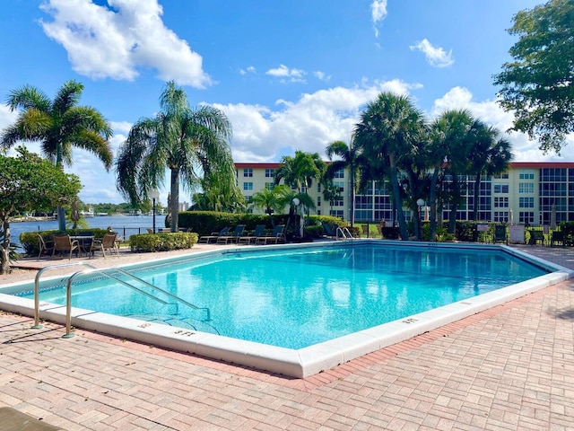 view of swimming pool featuring a patio and a water view