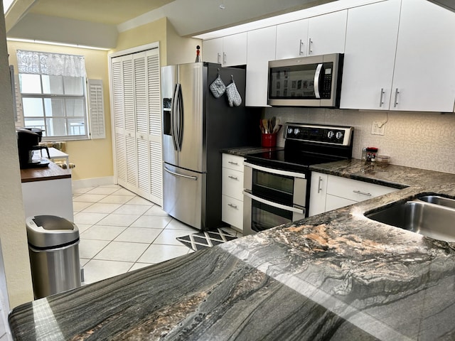 kitchen featuring light tile patterned flooring, tasteful backsplash, white cabinetry, sink, and stainless steel appliances