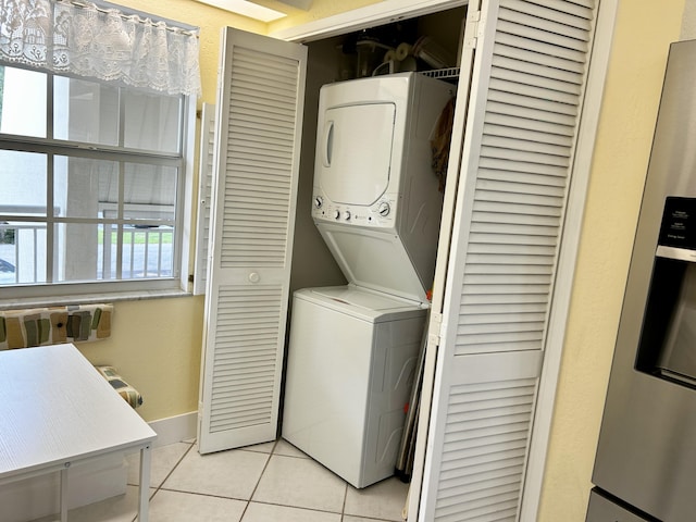 clothes washing area with stacked washer / drying machine and light tile patterned floors