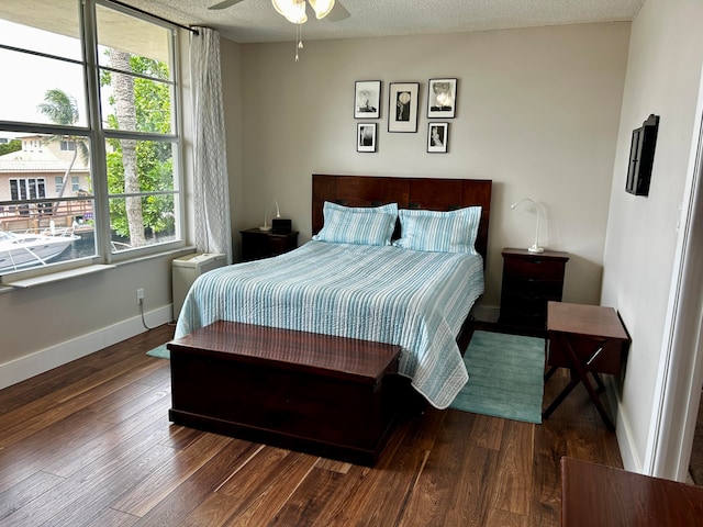 bedroom featuring multiple windows, dark wood-type flooring, and ceiling fan