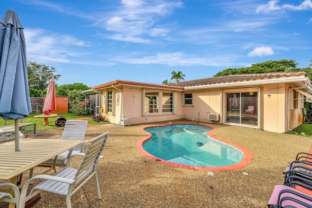 view of swimming pool featuring a wall mounted air conditioner and a patio