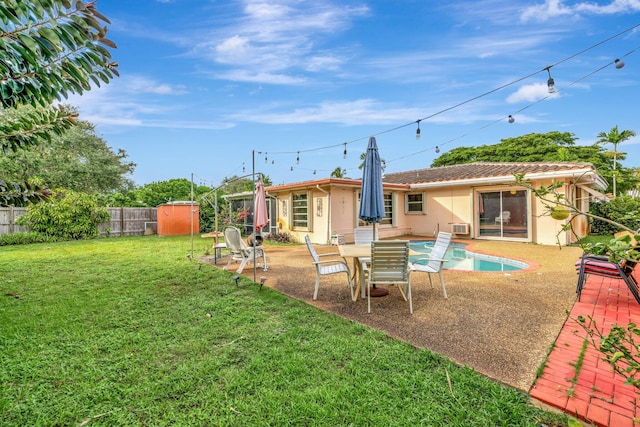 back of property featuring a lawn, a patio area, and a storage shed