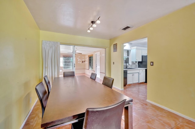 tiled dining room featuring rail lighting, ceiling fan, and sink