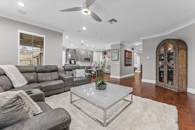 living area featuring a barn door, visible vents, a ceiling fan, ornamental molding, and wood finished floors