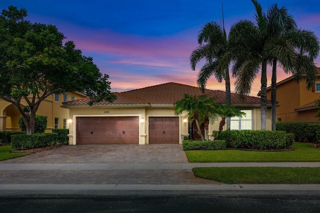 view of front of home with an attached garage, a tile roof, decorative driveway, and stucco siding