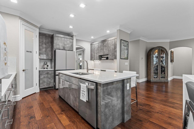 kitchen with arched walkways, dark wood finished floors, dishwasher, a kitchen island with sink, and a sink