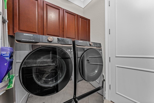 laundry room with cabinet space, washing machine and clothes dryer, and tile patterned floors