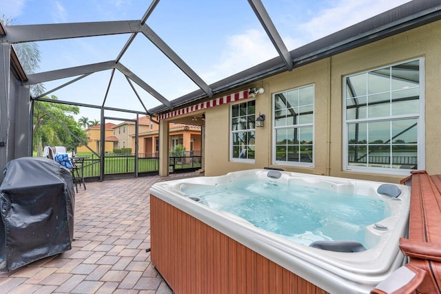 view of patio featuring glass enclosure, a hot tub, and grilling area