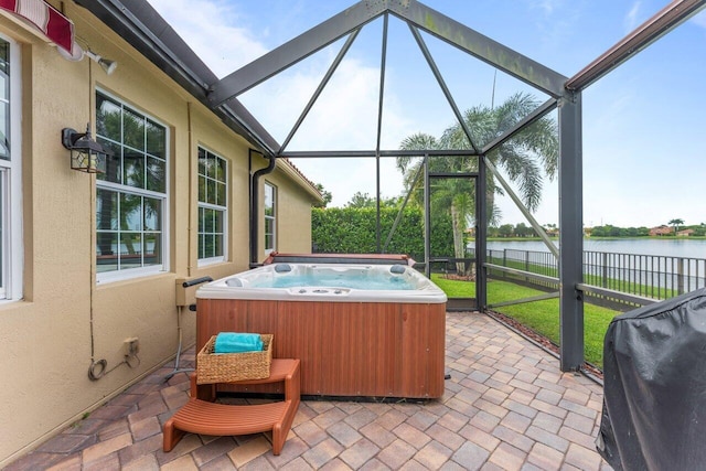 view of patio featuring a water view, glass enclosure, a hot tub, and a grill