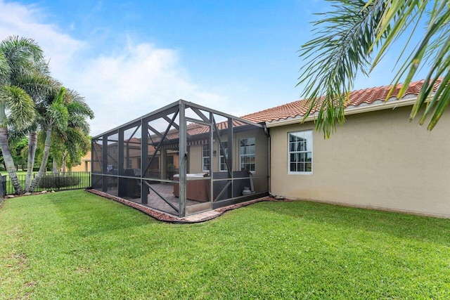 back of property featuring a tile roof, stucco siding, a lawn, glass enclosure, and fence