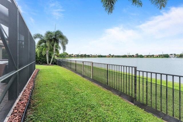 view of yard with a water view, a fenced backyard, and a lanai