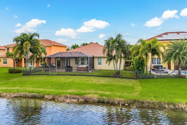 back of house with a water view, a lawn, a fenced backyard, and stucco siding