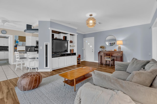 living room with ornamental molding, light wood-type flooring, and ceiling fan