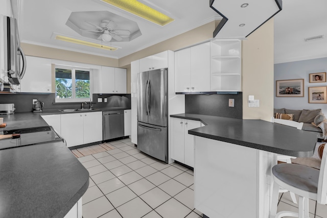 kitchen featuring kitchen peninsula, white cabinets, backsplash, appliances with stainless steel finishes, and a breakfast bar area