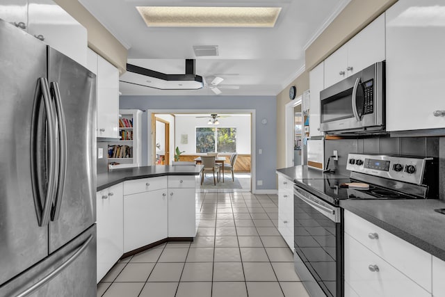 kitchen with appliances with stainless steel finishes, white cabinetry, crown molding, decorative backsplash, and light tile patterned floors