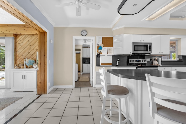 kitchen featuring ornamental molding, white cabinets, stainless steel appliances, and light tile patterned floors