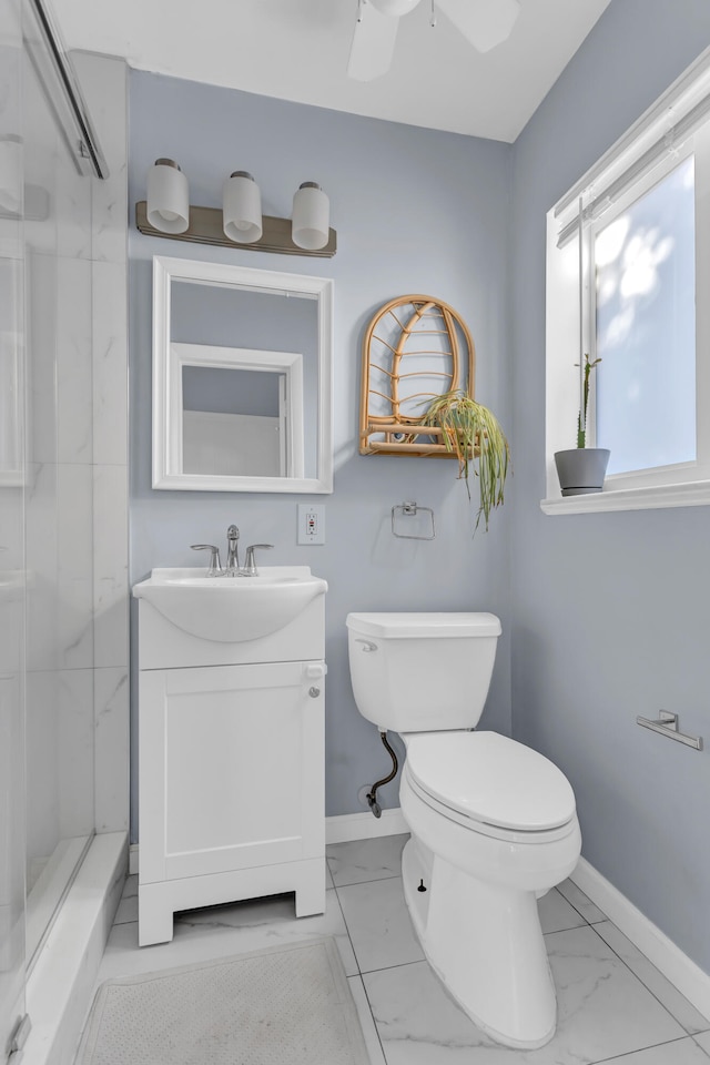 bathroom with toilet, ceiling fan, vanity, and tiled shower