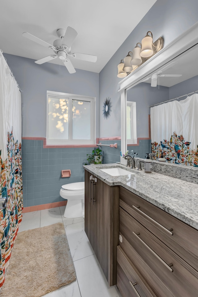 bathroom with vanity, toilet, tile walls, and ceiling fan