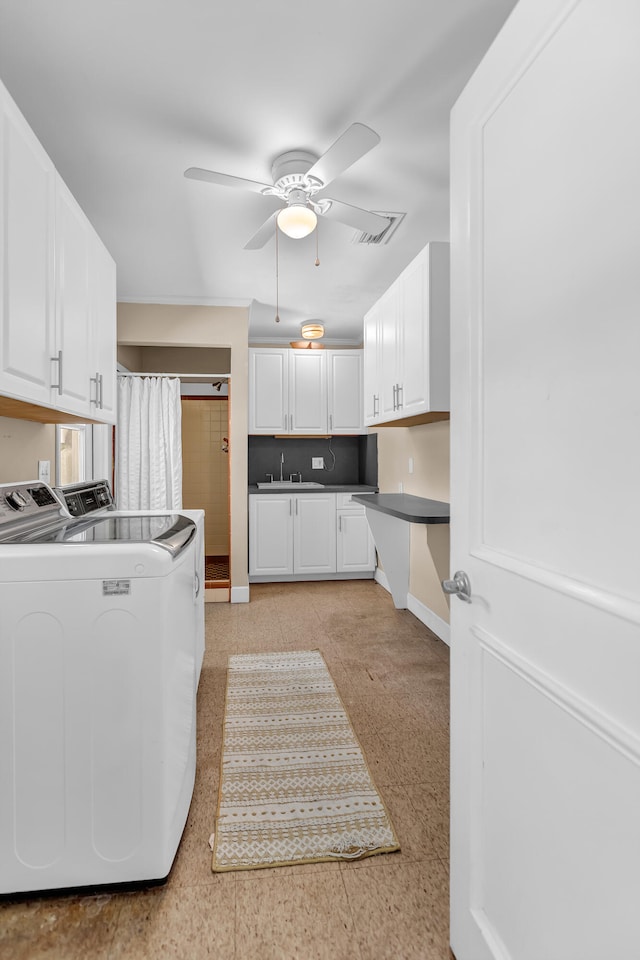 kitchen featuring washer and dryer, white cabinets, sink, and ceiling fan