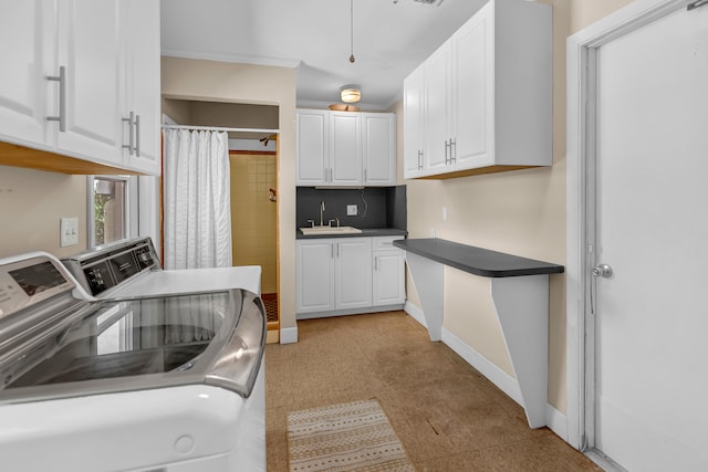 kitchen with white cabinetry, sink, and washing machine and clothes dryer