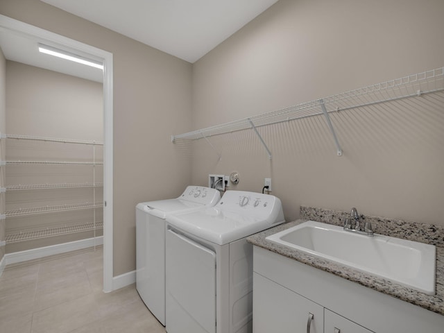 laundry area with sink, independent washer and dryer, and light tile patterned floors