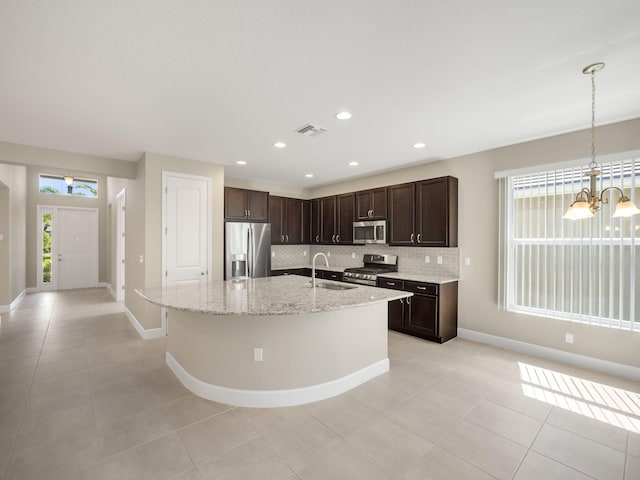 kitchen with a center island with sink, sink, stainless steel appliances, and tasteful backsplash