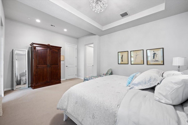 carpeted bedroom featuring a notable chandelier, a textured ceiling, and a tray ceiling