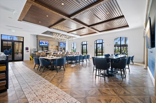 dining area with an inviting chandelier, french doors, parquet floors, and coffered ceiling