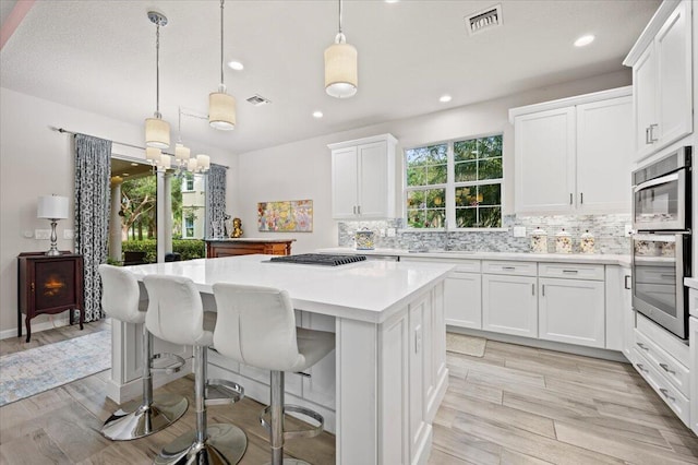 kitchen with a wealth of natural light, white cabinets, and pendant lighting