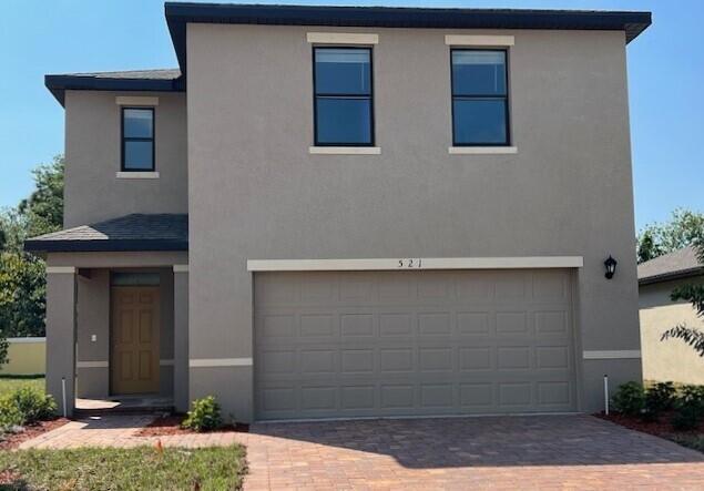 traditional home featuring decorative driveway, a garage, and stucco siding