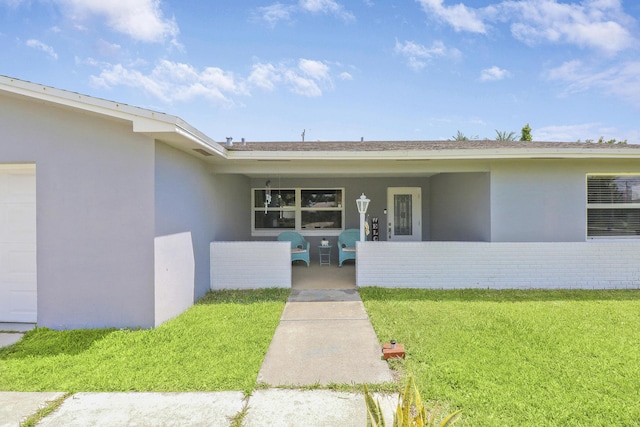 entrance to property with a lawn and stucco siding