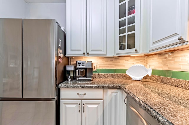 kitchen with white cabinets, stainless steel fridge, and tasteful backsplash