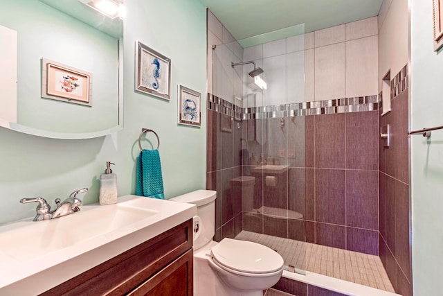 bathroom featuring tiled shower, vanity, and toilet