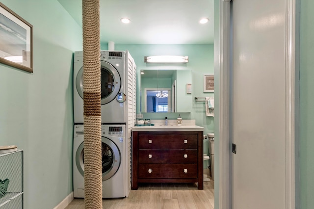 bathroom with wood-type flooring, stacked washer / dryer, vanity, and toilet