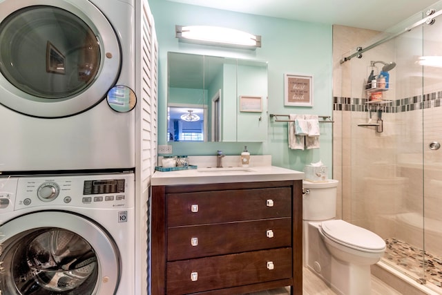 bathroom featuring stacked washer / dryer, a shower with shower door, vanity, and toilet