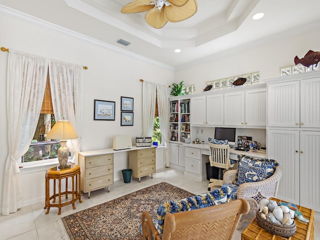 tiled office featuring ornamental molding, ceiling fan, built in desk, and a tray ceiling