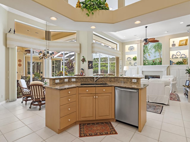 kitchen with dishwasher, dark stone counters, sink, and light tile patterned flooring